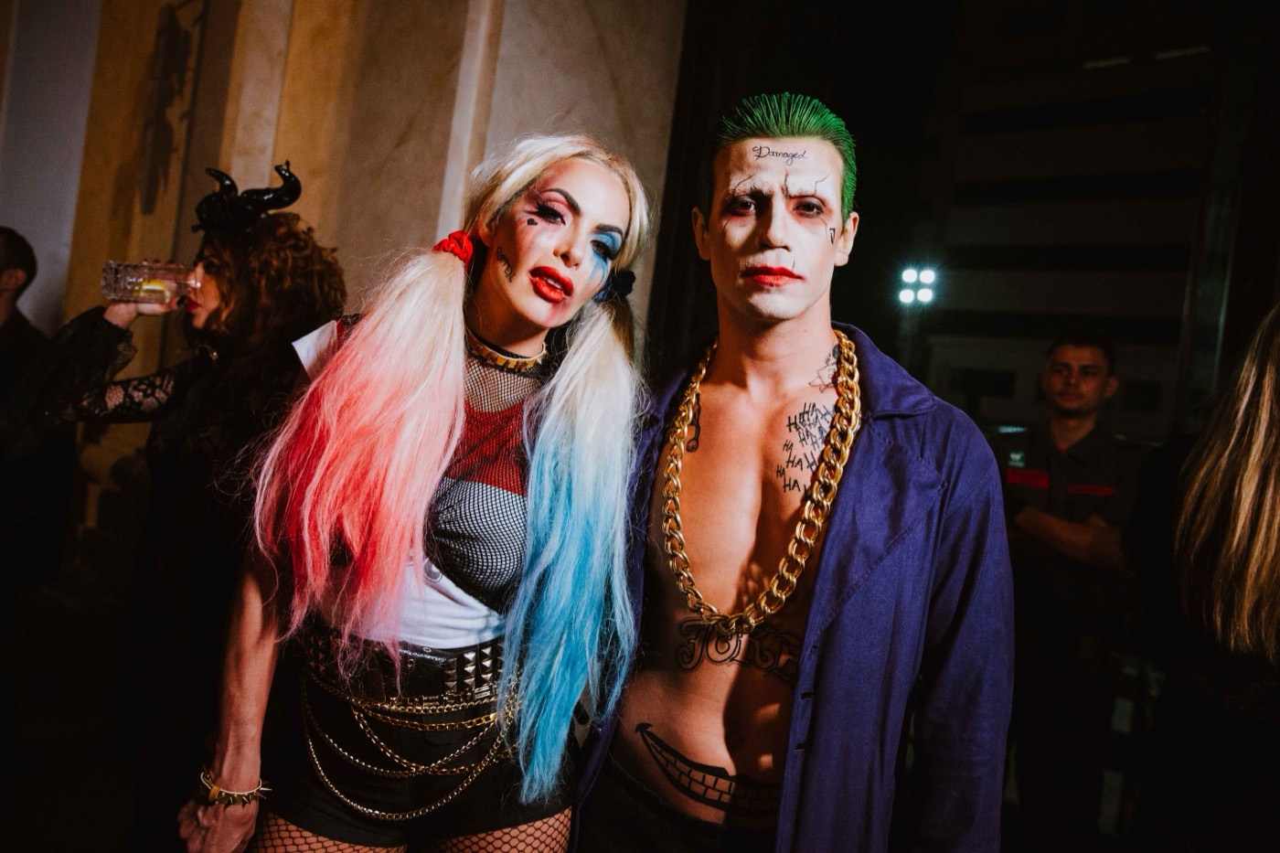 Two costumed people pose together, one with pink and blue pigtails, the other with green hair and a white face