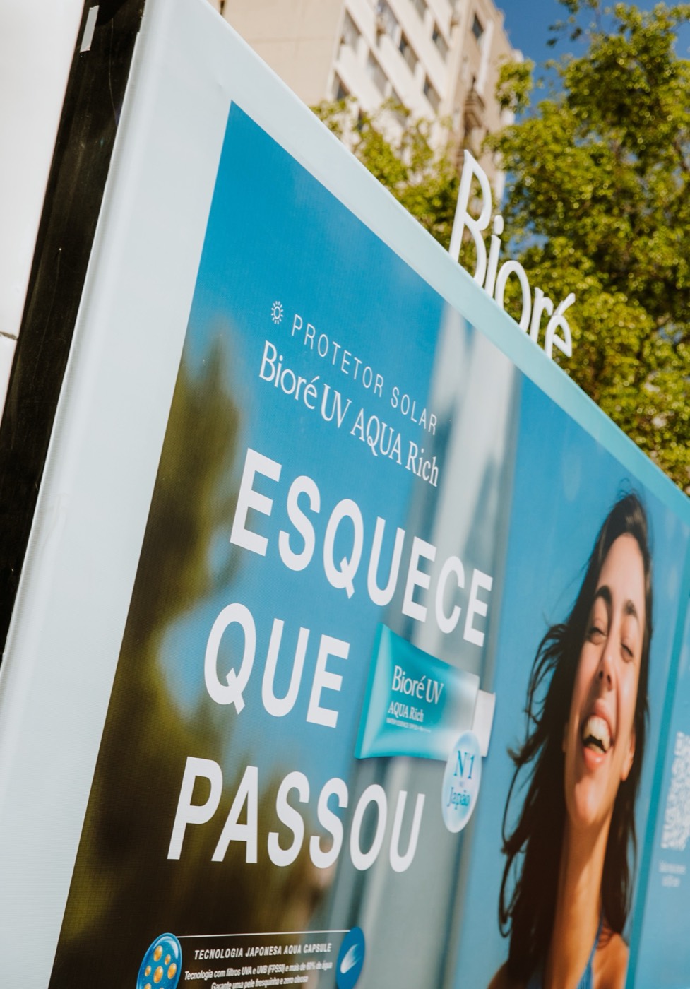 Truck side panel with the phrase "ESQUECE QUE PASSOU", an image of a smiling person and trees in the background