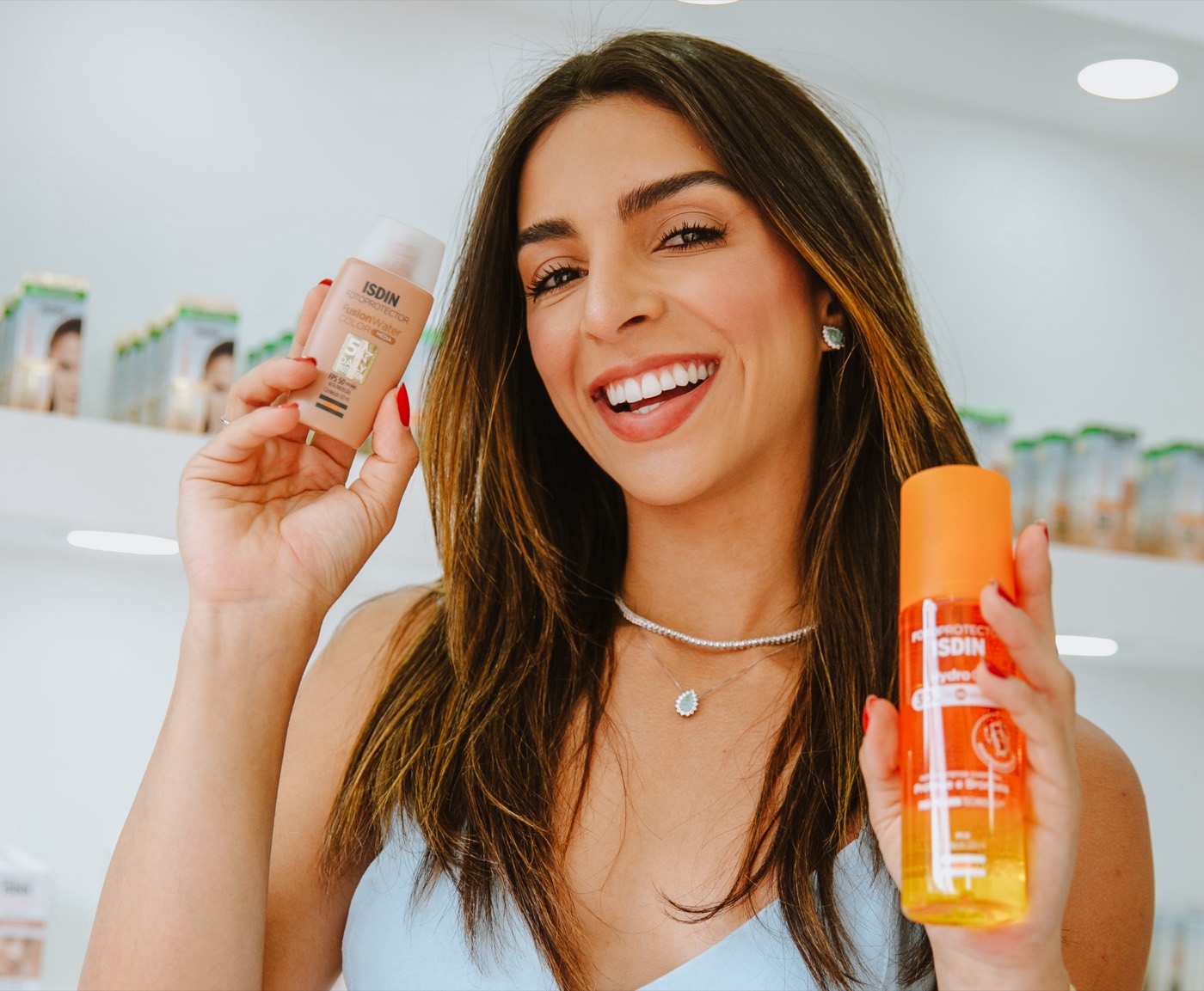 Smiling person holds two skincare products next to their face inside a white store