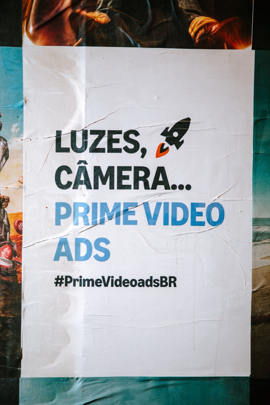 Poster pasted on a wall reading "LUZES, CÂMERA... PRIME VIDEO ADS #PrimeVideoadsBR"