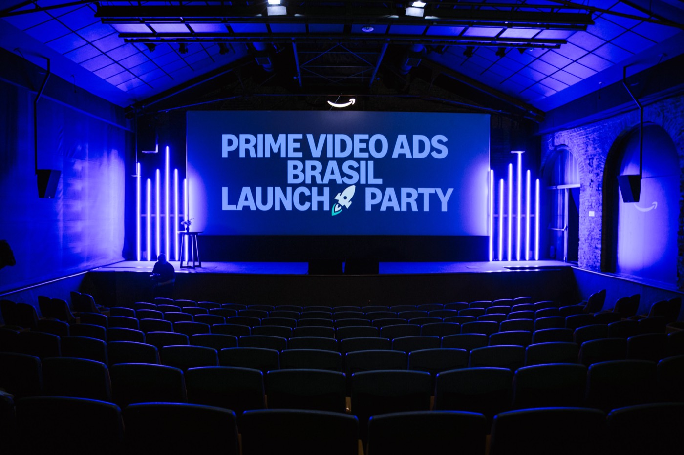 Empty auditorium in blue light with a screen showing "PRIME VIDEO ADS BRASIL LAUNCH PARTY"