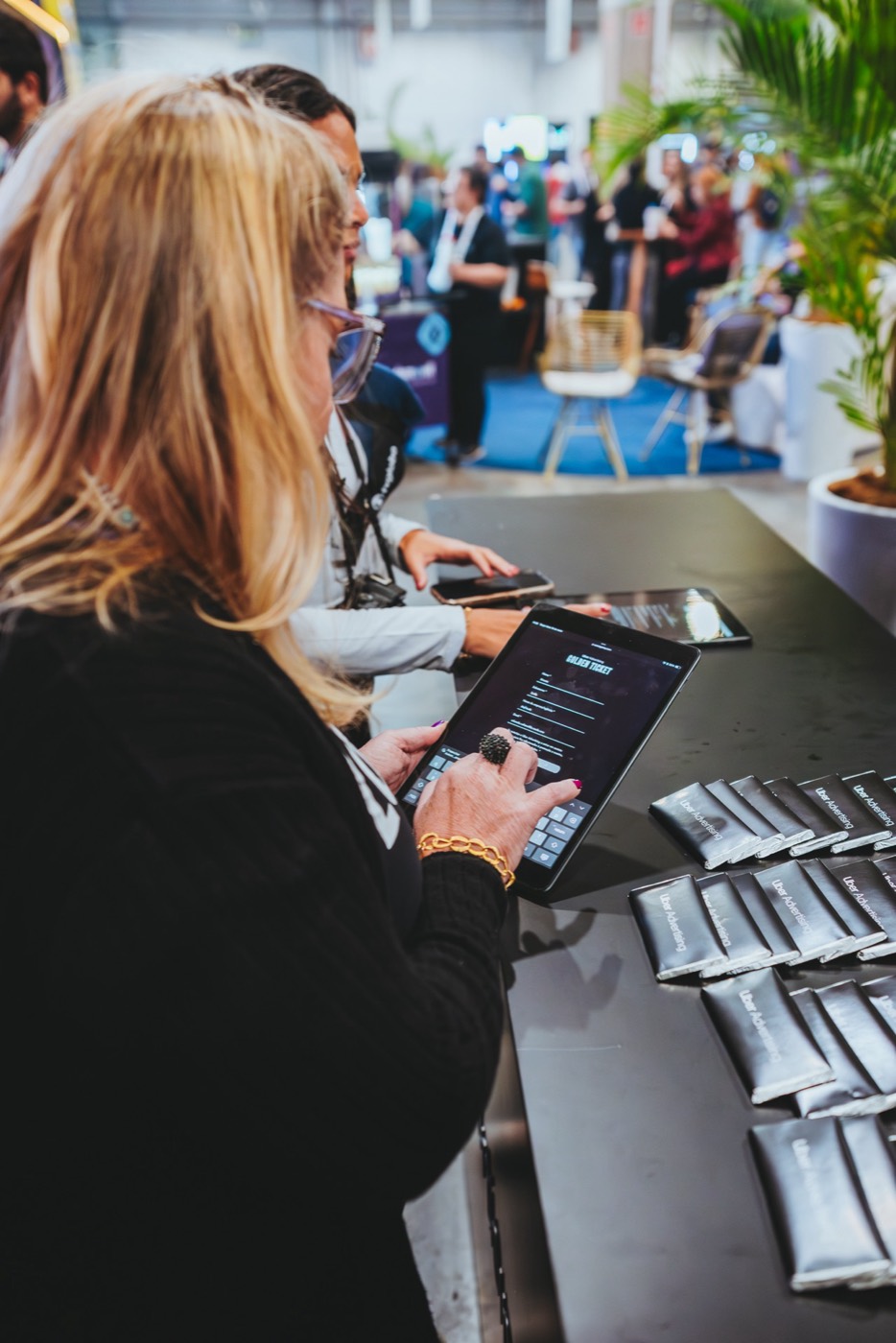 Person seen from behind types on a tablet at a black counter lined with wrapped bars at a trade show