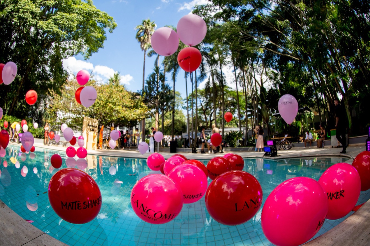 Close view of a pool with large red and pink balloons floating, some reading "LANCÔME" and "MATTE SHAKER"