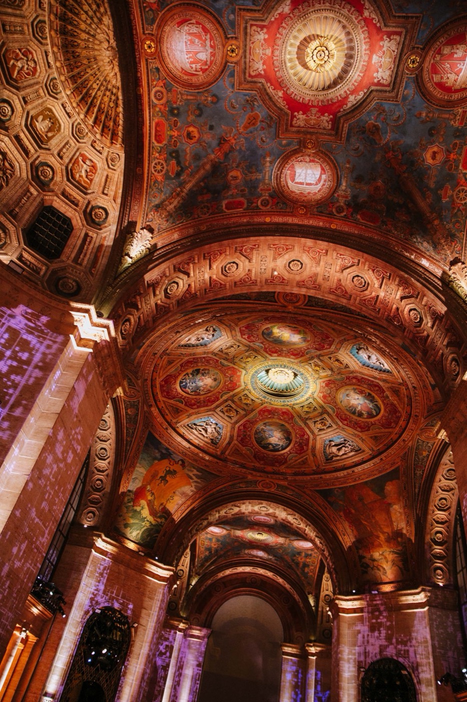 Richly ornamented vaulted ceiling, with painted domes and gilded details lit in warm tones